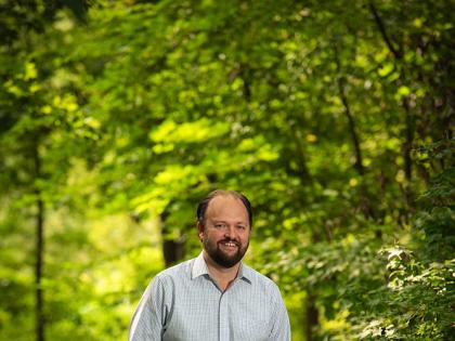 Ross Douthat standing in a wooded park