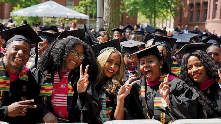 group of Harvard graduates in cap and gown celebrate