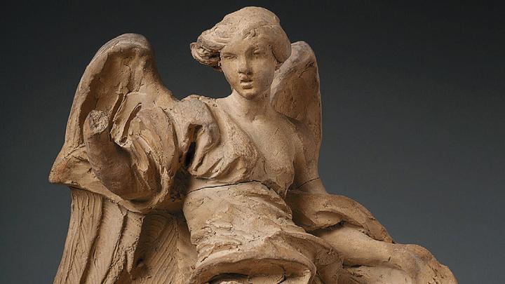 A clay sculpture of a robed angel. 
