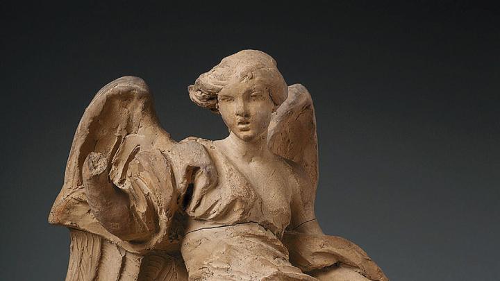 A clay sculpture of a robed angel. 
