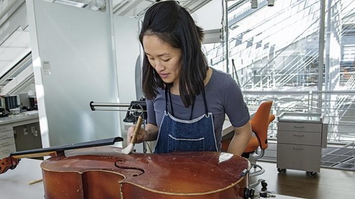 Angela Chang, assistant director and conservator of objects and sculpture, readying a cello for display.