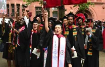Law School graduates in black caps and gowns cheer 
