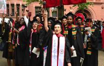 Law School graduates in black caps and gowns cheer 