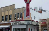 Photo of the exterior of Coolidge Corner Theater, with its vertical red neon sign.