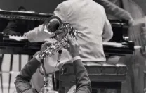 Jazz artist Walter Blanding playing the saxophone on his back on the floor, "demonstrating" styles of John Coltrane, 2002