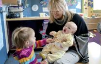 Mary Kinsella Scannell, vice president for early education and care, plays with baby Kinsey Ferraguto and toddler Margot Vorhees.