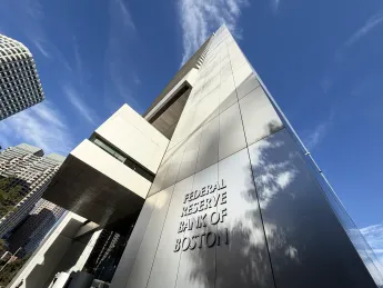 Modern building exterior with reflective surfaces against a blue sky.