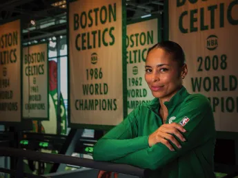 Allison Feaster wearing a green Celtics shirt in front of team championship banners
