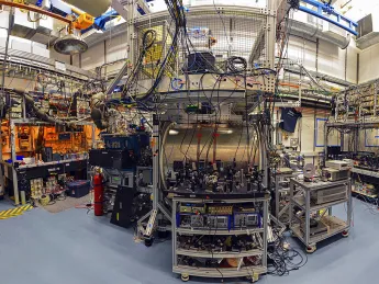 A complex laboratory setup with equipment, wires, and machinery in a spacious, well-lit room.