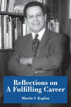 A man with crossed arms smiles in front of shelves filled with books.