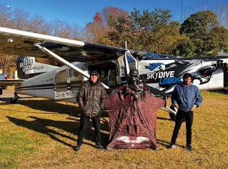 Alejandro Montagna standing in front of a small airplane wearing a wingsuit