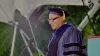 Man in blue faculty robe talks at podium