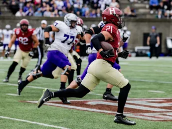 Harvard football player 21 runs with ball towards a touchdown with St. Thomas players pursuing