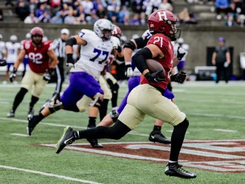 Harvard football player 21 runs with ball towards a touchdown with St. Thomas players pursuing