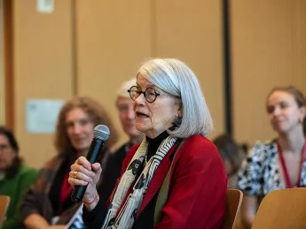 Diane Eck with microphone addressing group
