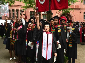 Law School graduates in black caps and gowns cheer 