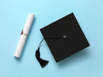 Graduation hat and diploma on color background