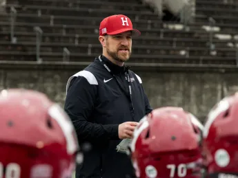Coach Andrew Aurich standing in the center among a crowd of football players in the foreground