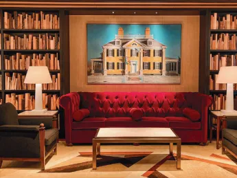 Library looking room with bookcases and a red sofa and accent chairs 