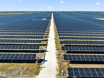 Vast solar farm with rows of solar panels under a clear blue sky.