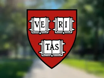 Harvard FAS shield in the foreground with Harvard Yard in a blurred background