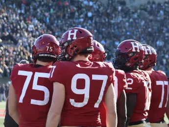 Crimson footballers on the sideline of the 2022 Harvard-Yale game