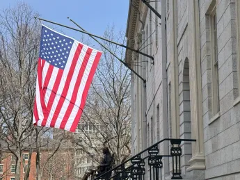 University Hall with a flag over the John Harvard Statue