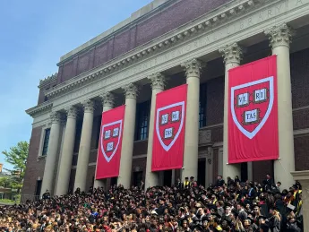Commencement flags at Widener with students gathered on steps