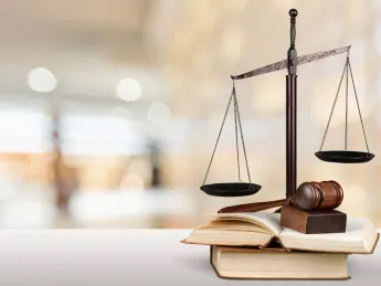 Scales of justice and a gavel resting on open law books with a blurred courtroom background.