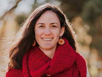 A smiling woman in a red scarf with brown hair