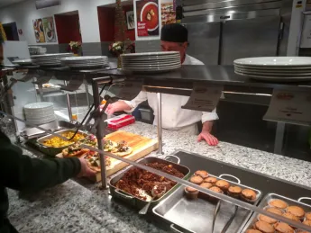 Vegan muffins, hash, bacon, and other plant-based options are served at a cafeteria counter