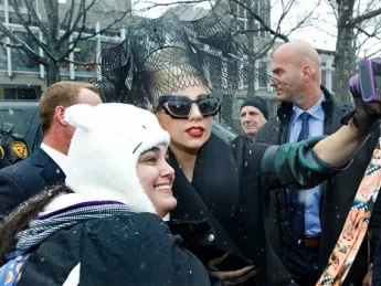Lady Gaga poses with a fan near the Science Center before the Sanders Theatre panel.