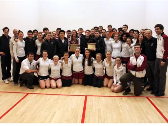 The men's and women's squash teams pose with their coaches—and their trophies.
