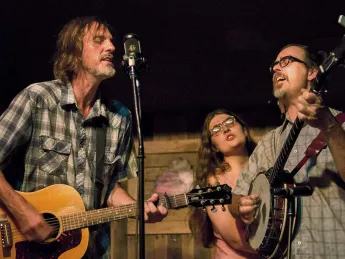 A bluegrass guitarist, banjoist, and singer perform on stage