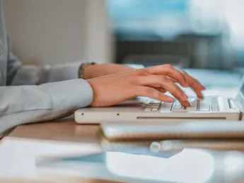 Hands typing on a computer keyboard.
