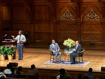 Martin Luther King III and Brandon Terry seated in chairs on a large auditorium stage