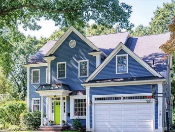 Exterior of blue house with garage surrounded by greenery