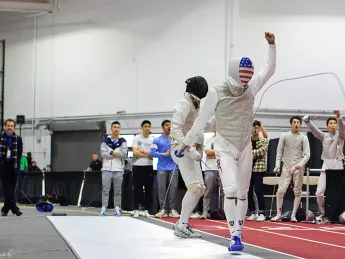 A fencer walks away from his opponent, holding up a fist