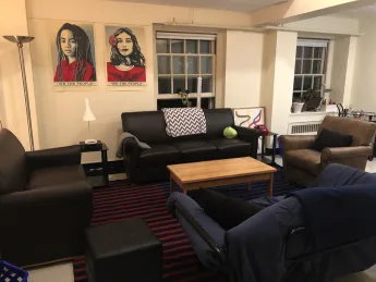 Photograph of the author's Harvard dorm room with chairs, sofa, posters