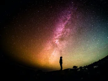 silhouette of person looking up from the ground at sky 