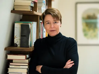 Ophelia Dahl, standing in front of a bookshelf with her arms crossed