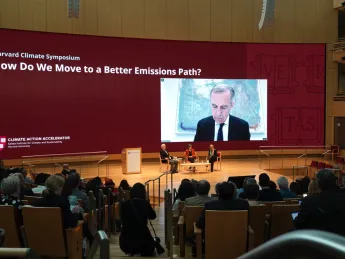 A plenary session at the Harvard Climate Symposium featured Jeremy Grantham, Janet McCabe, Gillian Tett (moderating), and via video link, Mark Carney.