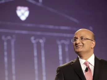 “Let’s begin”: Business School dean Nitin Nohria during his campaign address April 25; a sketch of the iconic Baker Library is projected behind him.