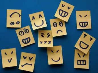 Multiple small paper tabs, each decorated with a simple line drawing of a different facial expression
