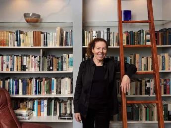 Wendy Lesser standing happily among her books 