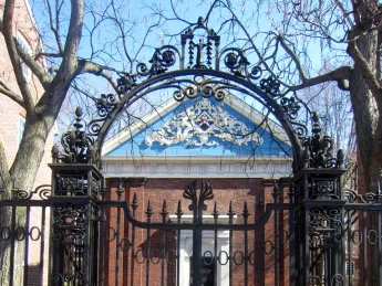 The arch of the delicate Class of 1870 Gate acts like a raised eyebrow, perfectly framing a view of Holden Chapel's ornate blue gable. The gate has been locked for decades, preventing pedestrians along Massachusetts Avenue from entering the chapel's intimate courtyard.