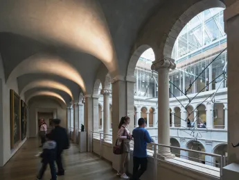 A few visitors in the arcade overlooking the Calderwood Courtyard of the Harvard Art Museums