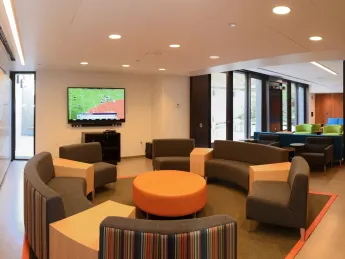 Couches, a flat-screen TV, multicolored chairs, and a brand-new kitchen have transformed the basement of the newly renovated Old Quincy into an appealing community room.
