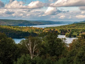 sweeping aerial view of blue sky and Quabbin Reservoir water and mountains 