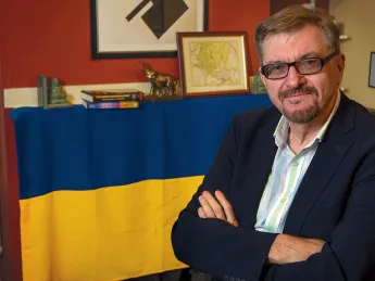 Serhii Plokhy in his Harvard office, smiling with his arms crossed. Behind him hangs a Ukrainian flag signed by Kyiv mayor Vitali Klitschko